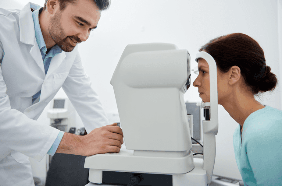 Profissional de saúde ajustando equipamento de exame ocular enquanto paciente realiza teste de visão.